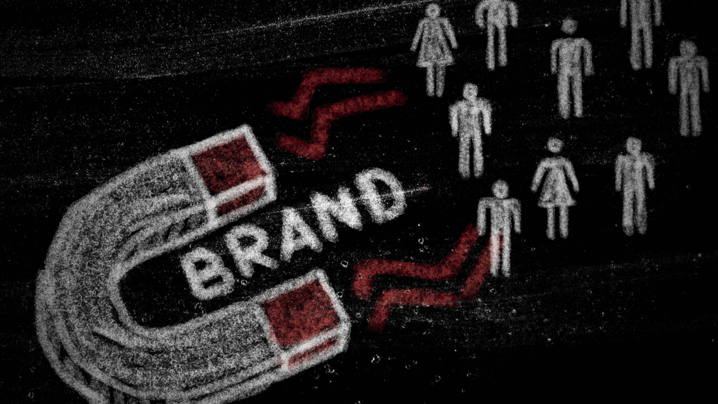 صورة ذات طابع درامي وداكن مرسومة على خلفية تشبه السبورة السوداء، تُظهر مغناطيساً كبيراً مرسوماً بالطباشير يسحب مجموعة من الرموز البشرية المصغرة نحوه. المغناطيس يحمل كلمة "BRAND" (العلامة التجارية) باللون الأبيض والأحمر. هذه الصورة تمثل بوضوح مفهوم قوة العلامة التجارية في جذب العملاء المحتملين وبناء الولاء للعلامة التجارية. إنها تجسد الجانب الاستراتيجي في التسويق الذي يركز على جعل البراند جاذباً بما يكفي لدفع الناس نحو المنتج دون الحاجة إلى جهد إعلاني مباشر. الصورة ممتازة لمقالات استراتيجية البراند وتأثير قيمة البراند في السوق.