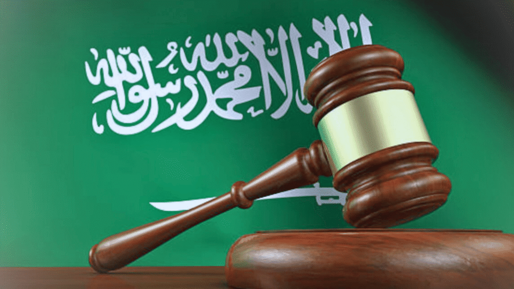 مطرقة قاضٍ أمام علم المملكة العربية السعودية ترمز إلى العدالة والقضاء السعودي.