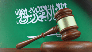 مطرقة قاضٍ أمام علم المملكة العربية السعودية ترمز إلى العدالة والقضاء السعودي.